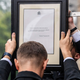 Two men at Buckingham Palace in England hold a message announcing Queen Elizabeth II's death